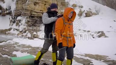 两个人去冬季远足。 朋友们有专业的设备，他们沿着悬崖走。